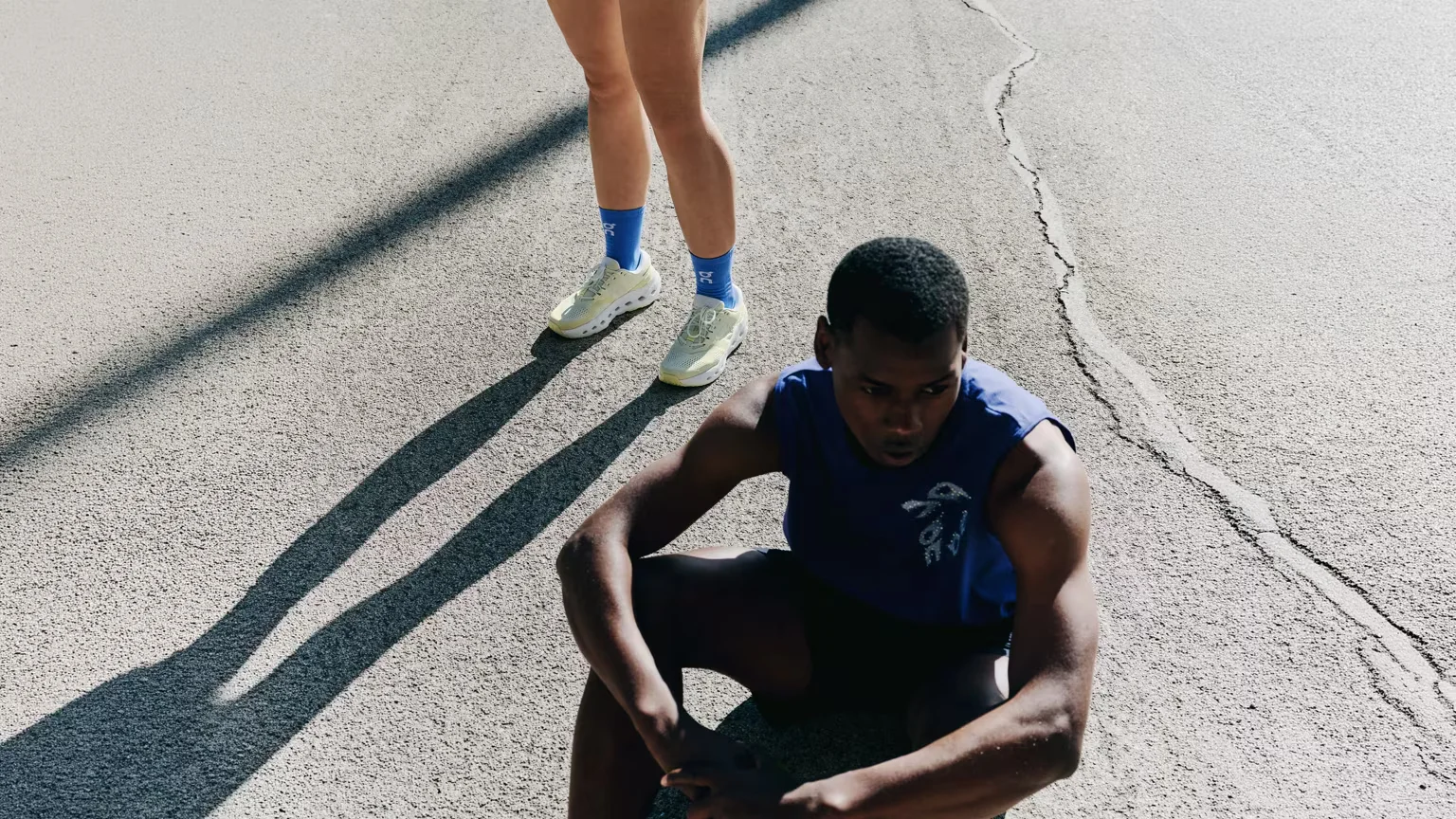 Person sitting on pavement, sunny day.