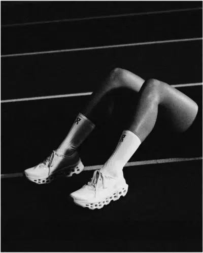 Runner legs on track, wearing On Running Cloud shoes with signature CloudTec sole